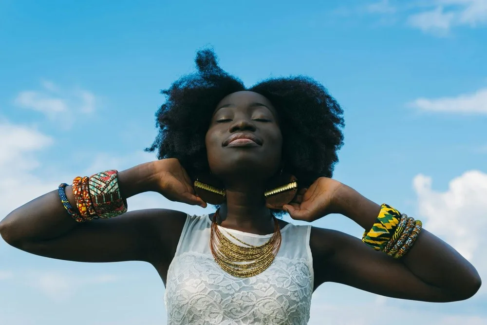 Fille noire coupe afro avec des bracelets colorés aux poignets